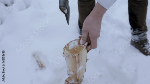 From above of male lumberjack cutting wood with axe in snowy winter forest 