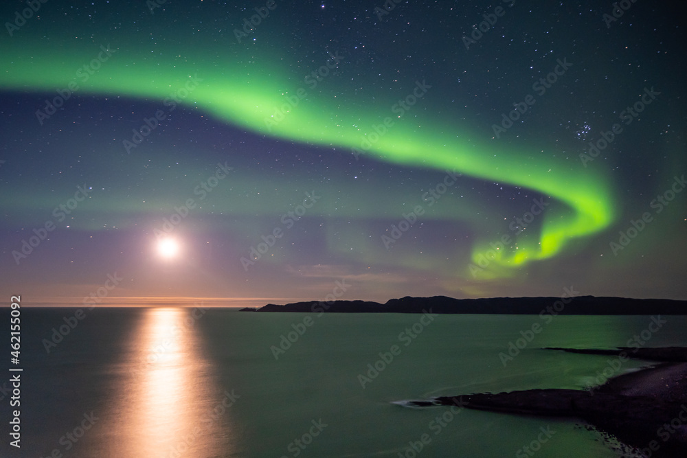 Bright green nortern lights on the shore of Barents sea in Teriberka