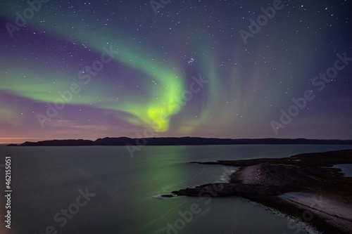 Bright green nortern lights on the shore of Barents sea in Teriberka © Elena