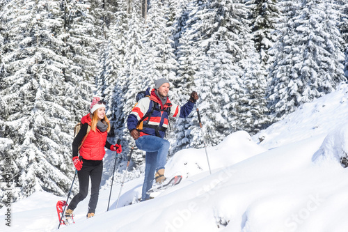 Man snowshoeing with woman on snow during winter