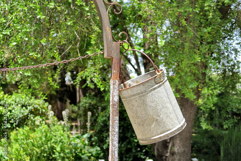 Seau de métal accroché à un puits dans un jardin. Seau de métal accroché à un puits dans un jardin.