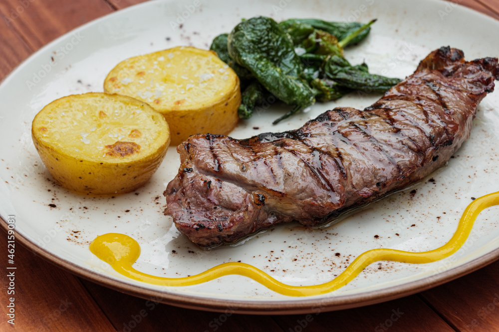 Delicious fried juicy beef on a plate with potatoes and green peppers Delicious fried juicy beef on a plate with potatoes and green peppers