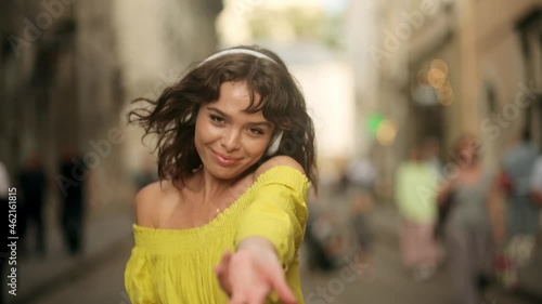 Funky woman dancing alone in the street. Happy young woman in wireless headphones dancing singing outdoors in city street having fun alone