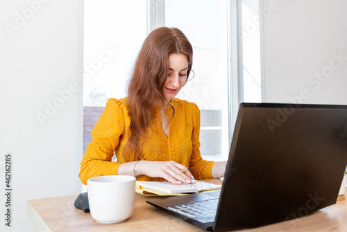 Defocus. Young woman is education online by using computer. Female freelancer browsing laptop.