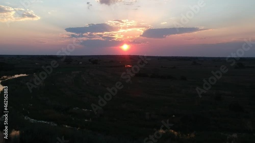 Red and gold African sunset camera rising up over reeds of a wetland reflection of red sunlight on the Kwando river Aerial Video. Kwando River, Mudumu, Caprivi, Namibia photo