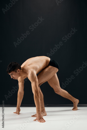 male bodybuilder in black shorts on a dark background