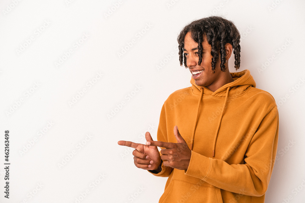 Young african american man isolated on white background points with thumb finger away, laughing and carefree.