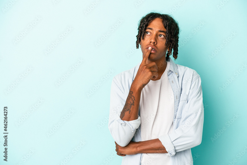 Young african american man isolated on blue background looking sideways with doubtful and skeptical expression. Young african american man isolated on blue background looking sideways with doubtful and skeptical expression.