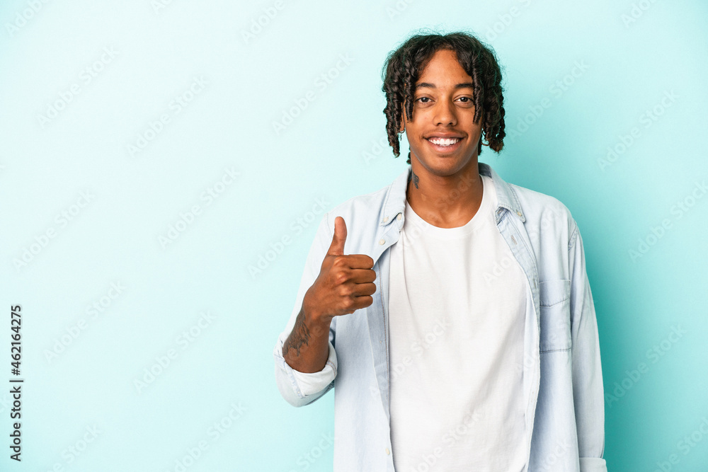 Young african american man isolated on blue background smiling and raising thumb up Young african american man isolated on blue background smiling and raising thumb up