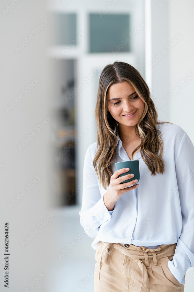 Female business professional holding coffee cup in office