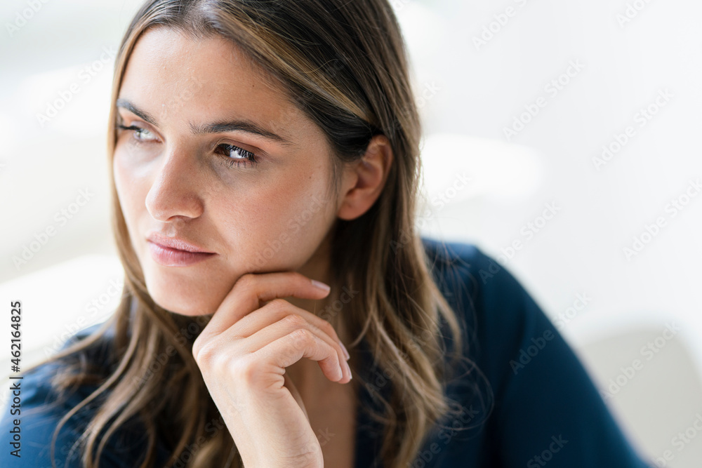Thoughtful businesswoman with hand on chin in office Thoughtful businesswoman with hand on chin in office