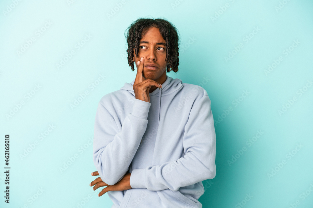 Young african american man isolated on blue background contemplating, planning a strategy, thinking about the way of a business. Young african american man isolated on blue background contemplating, planning a strategy, thinking about the way of a business.