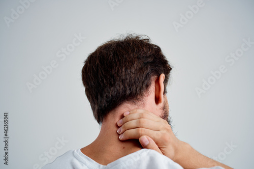 bearded man in a white t-shirt stress medicine pain in the neck light background