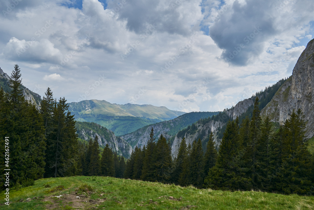 Scorota sheepfold in Retezat mountain with peak forest blue sky
