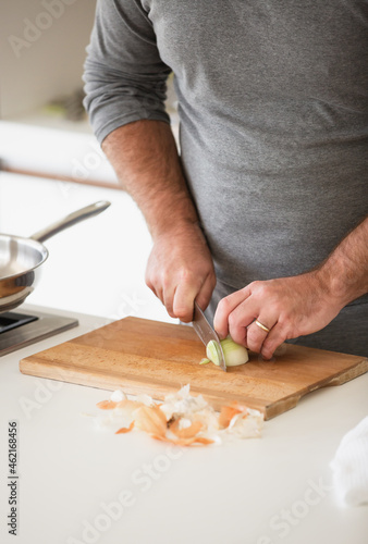 Man cutting vegetables on wooden desk in home kitchen