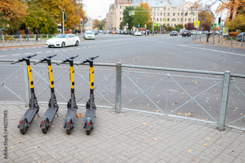 Scooter-sharing system parking lot in the city center, roadway in the background. Autumn, yellow shades
