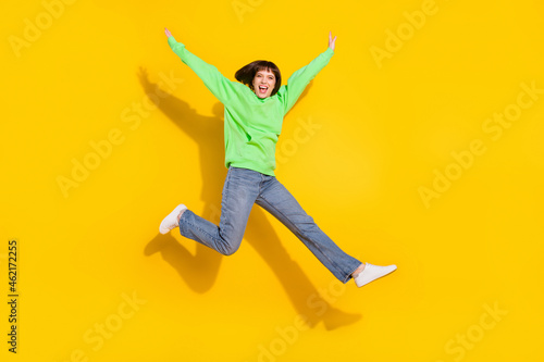 Full length body size view of attractive cheerful girl jumping walking having fun isolated over bright yellow color background © deagreez