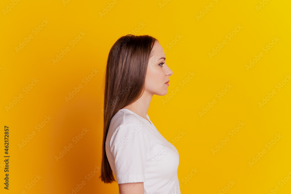 Profile side photo of young girl calm serious look empty space wear casual white t-shirt isolated over yellow background Profile side photo of young girl calm serious look empty space wear casual white t-shirt isolated over yellow background