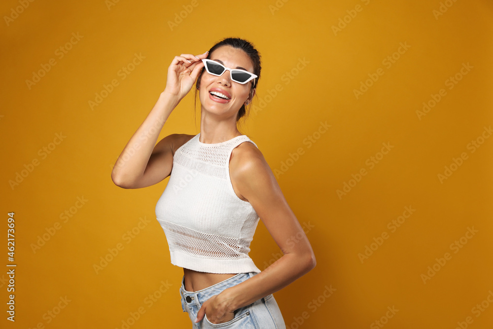 Beautiful woman in sunglasses on yellow background, space for text Beautiful woman in sunglasses on yellow background, space for text