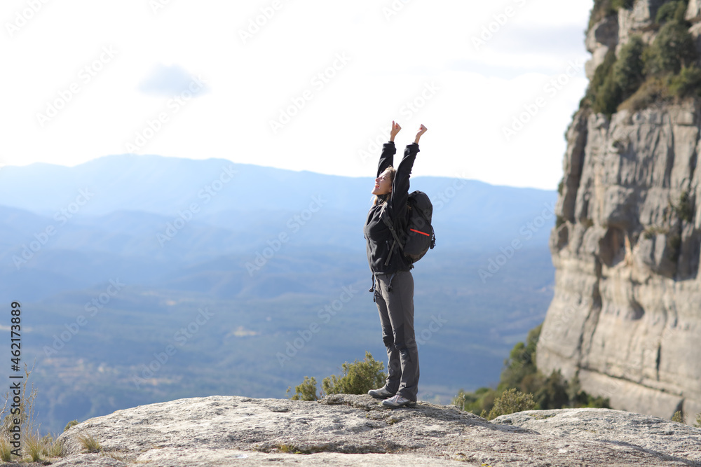Trekker raising arms in a cliff