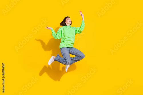 Full length body size view of attractive cheerful girl jumping using gadget browsing web isolated over bright yellow color background