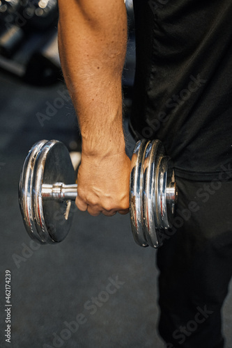 a man's hand holds a dumbbell in the gym