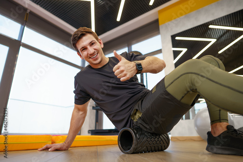 The man is massaging his leg muscles with the foam roller