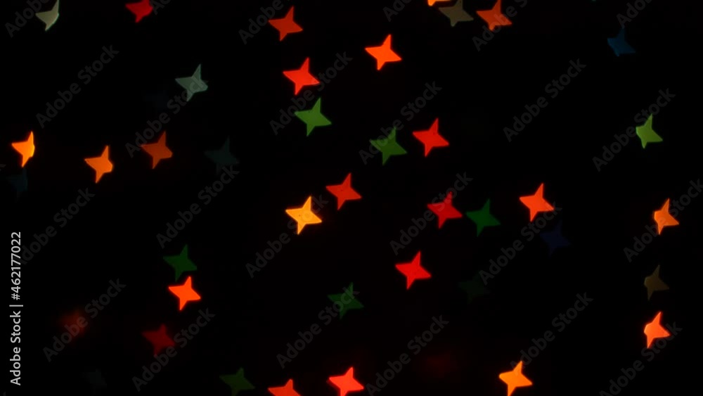 Flashing bokeh lights stars on decorative garland on black background. Festive blinking green, blue, red and yellow. Concept: Christmas, New Year, Holiday. Flashing bokeh lights stars on decorative garland on black background. Festive blinking green, blue, red and yellow. Concept: Christmas, New Year, Holiday.