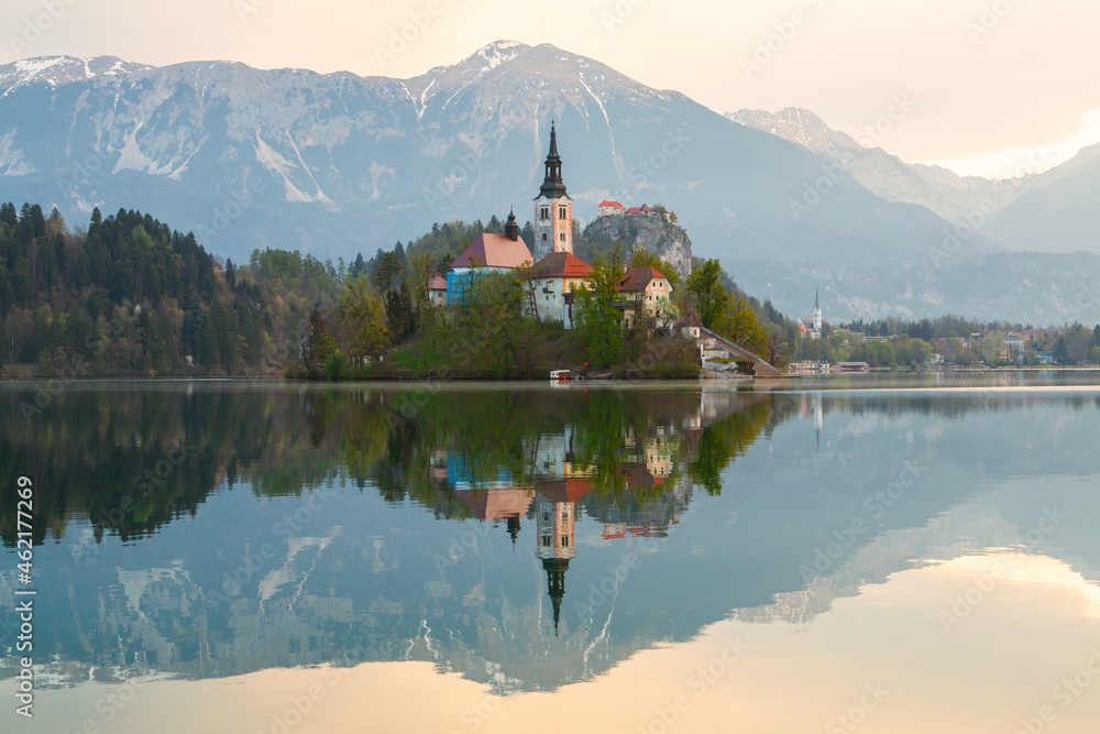 Beautiful cozy Lake Bled and the church on the island in the background with castle in the morning lights in the Julian Alps