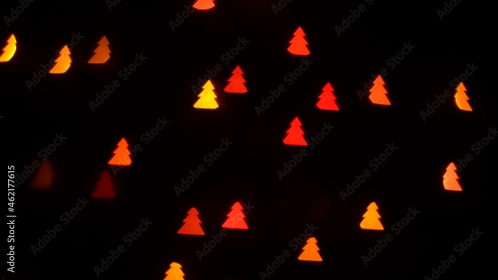 Flashing bokeh lights christmas trees on decorative garland on black background. Festive blinking green, blue, red and yellow. Concept: Christmas, New Year, Holiday. Flashing bokeh lights christmas trees on decorative garland on black background. Festive blinking green, blue, red and yellow. Concept: Christmas, New Year, Holiday.