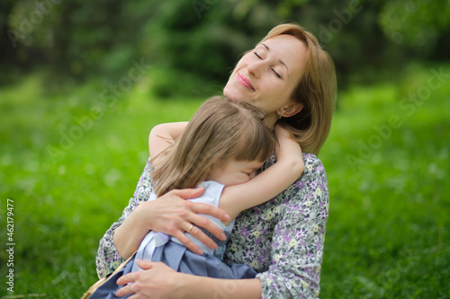 Side view close up head shot happy cute daughter hugging embracing cuddling mother. Concept of happy family. Portrait happy smiling child hugging mother in summer day