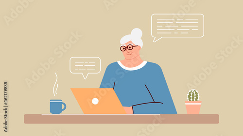 Senior woman studies and studies modern technologies using a laptop. A positive smiling grandmother sits at a computer, communicates on the Internet online and learns new things. An adult is working.