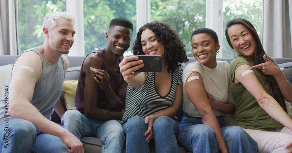 Group of diverse young people showing their vaccinated shoulders and taking a selfie at home Group of diverse young people showing their vaccinated shoulders and taking a selfie at home