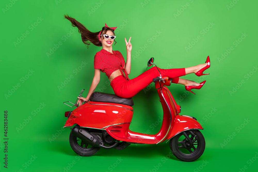 Photo of friendly tourist lady ride scooter show v-sign wear blouse headband high-heels isolated green color background Photo of friendly tourist lady ride scooter show v-sign wear blouse headband high-heels isolated green color background