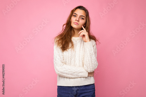 Portrait of young attractive caucasian hipster woman in trendy casual clothes. Sexy carefree female person posing isolated near pink wall in studio. Positive self-confident serious model with natural
