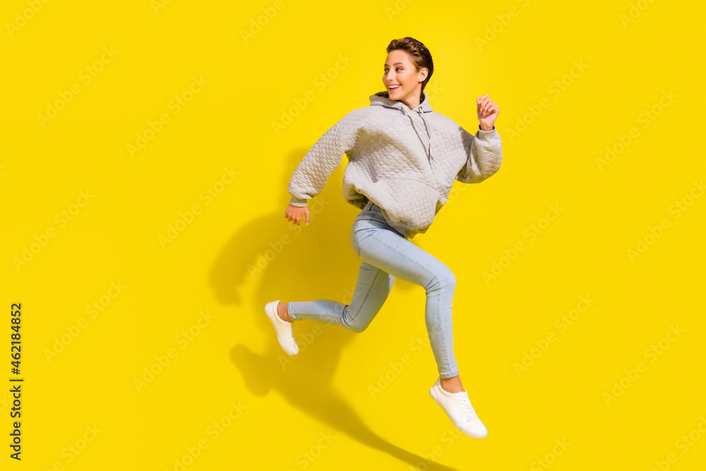 Full length photo of cute brown hair millennial lady run look wear sweater jeans sneakers isolated on yellow background
