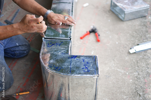 A worker is assembling a plugged-in air duct.

