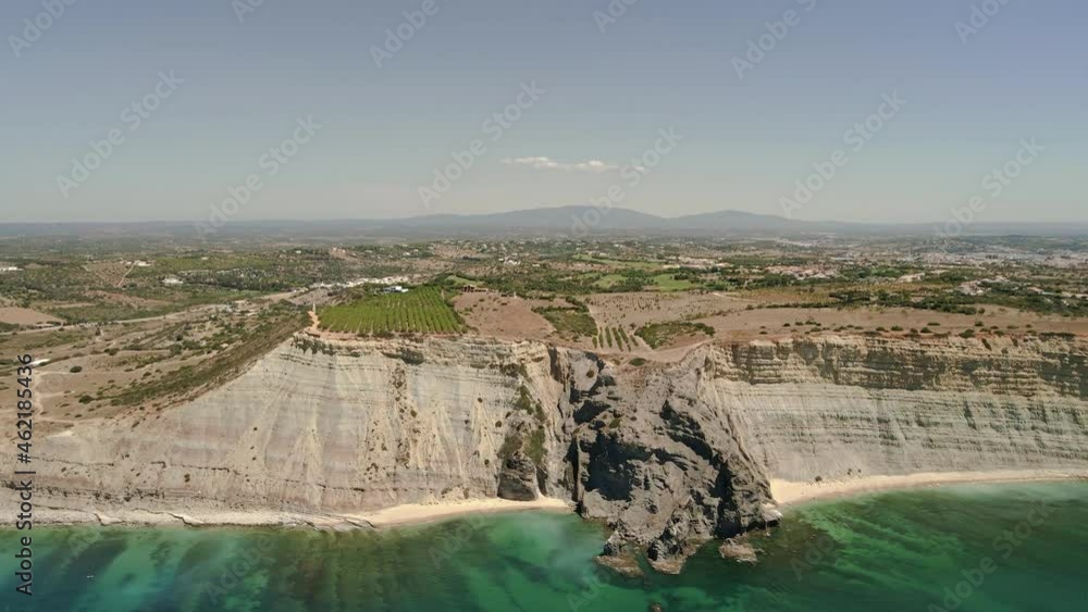 Aerial seascape of Rocha Negra (Black Rock), a black granite cliff created from volcanic action that carves through sandstone cliffs more common in Algarve tourist destination region, Portugal. Aerial seascape of Rocha Negra (Black Rock), a black granite cliff created from volcanic action that carves through sandstone cliffs more common in Algarve tourist destination region, Portugal.