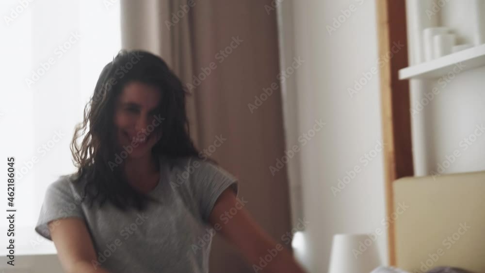 Millennial lifestyle. Carefree youth. Weekend joy. Achievement success. Happy playful overjoyed smiling cute young woman silly dancing on bed in light cozy bedroom. Millennial lifestyle. Carefree youth. Weekend joy. Achievement success. Happy playful overjoyed smiling cute young woman silly dancing on bed in light cozy bedroom.