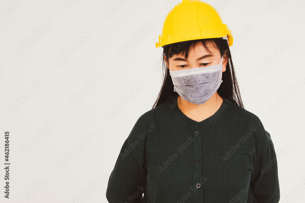 Asian female workers wear yellow safety helmets and wear protective masks that are stressful and weary from PM2.5 dust.