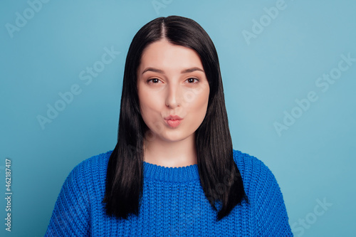 Portrait of lovely lady look in camera with lips pouted air kiss send concept isolated over blue color background © Tetiana