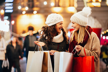 Happy women friends are shopping for presents at Christmas. People holiday sale shopping concept