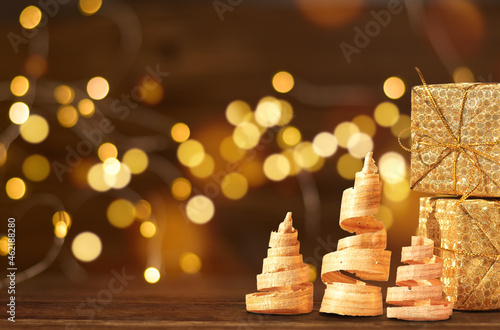 christmas trees and gift boxes on a wooden background against bokeh