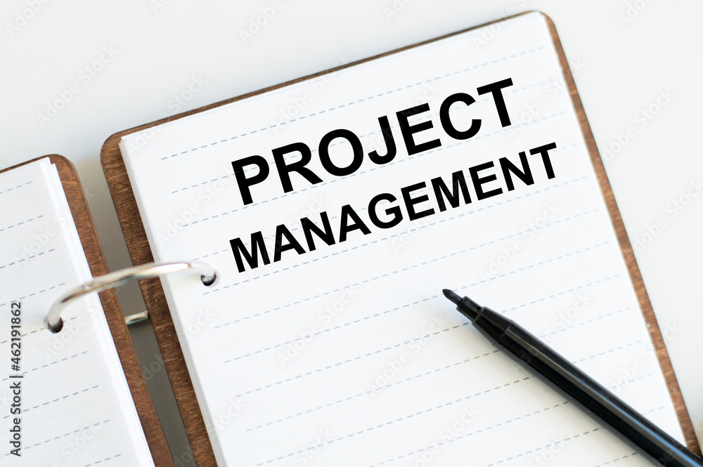 Notebook with text Project Management beside black marker Notebook with text Project Management beside black marker