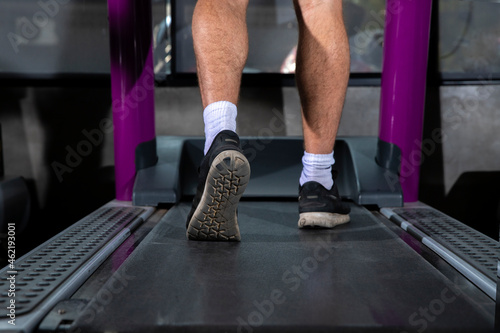 Close up foot sneakers Fitness man running on track treadmill, sportman with muscular legs in exercise gym