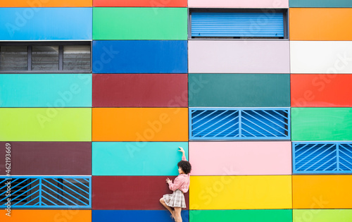 Young dancer standing with hand raised by colorful building photo