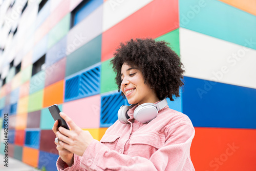 Smiling woman with headphones using mobile phone