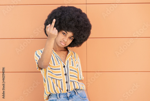 Young woman showing middle finger in front of wall photo