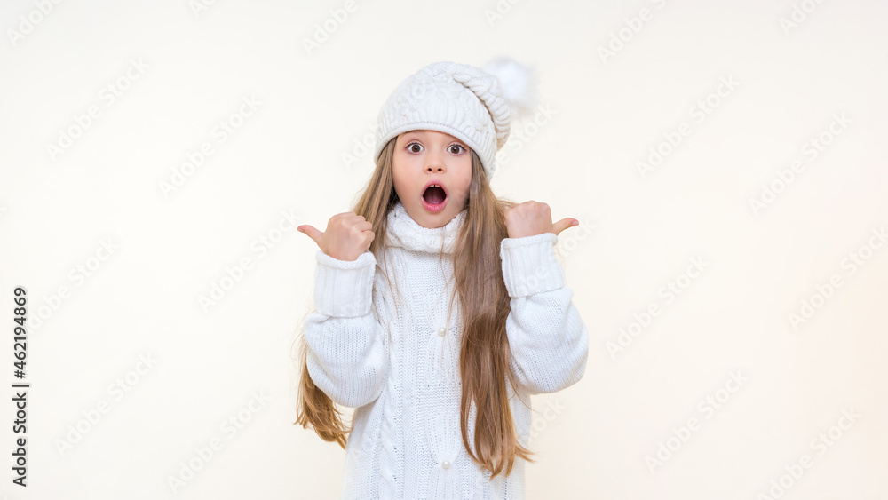 A surprised little girl with her mouth open points her fingers to the sides. isolated background. A surprised little girl with her mouth open points her fingers to the sides. isolated background.