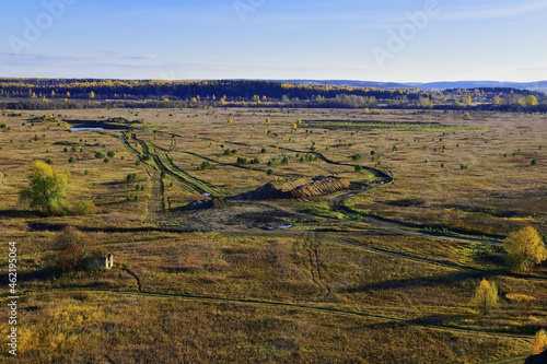 Car track on a field with dry grass in the oblique rays of the sun